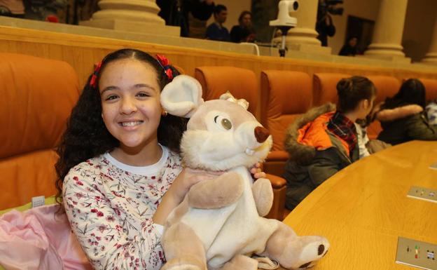 Una niña juega con un muñeco en una de las bancadas del Parlamento de La Rioja con motivo del Día del Niño. 