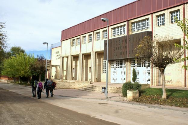 Unos peregrinos transitan por delante del polideportivo Sancho III el Mayor de Nájera. :: 