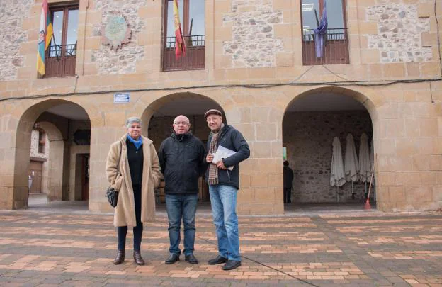 La concejal María Ascensión Voto; el alcalde, Isaac Palacios, y el maestro jubilado Ángel de la Riva, en la plaza de la localidad. :: albo