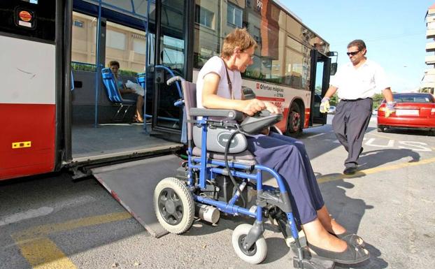 Una mujer en silla utiliza la rampa de acceso de un autobús urbano. 