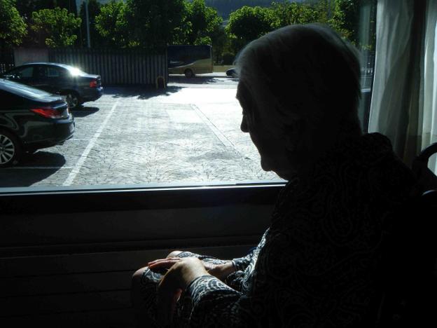 Una anciana observa la calle desde una ventana de una residencia de mayores. :: Jose Montes