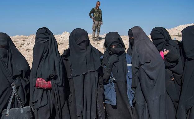 Varias mujeres caminan en Siria ante la mirada de las fuerzas militares. 