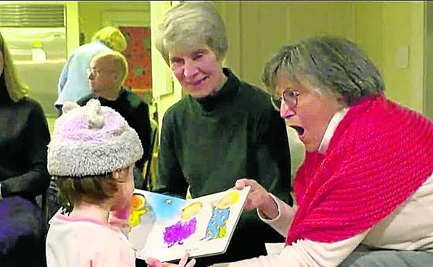 Dos mujeres muestran dibujos a la niña. 