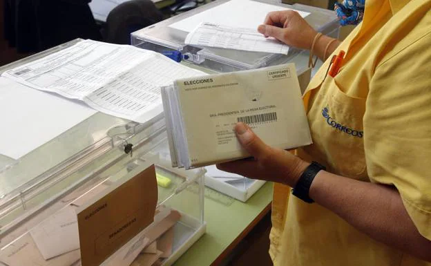 Un cartero introduce el voto por correo en las urnas de un colegio electoral.