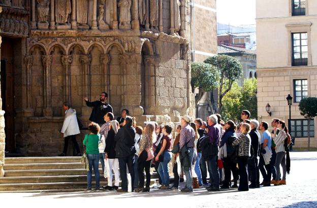 Un grupo de turistas asiste a las explicaciones de un guía a las puertas de San Bartolomé antes de acceder a su interior. :: 