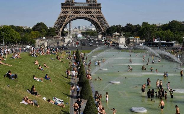La gente se refresca en unas fuentes cercanas a la Torre Eiffel.