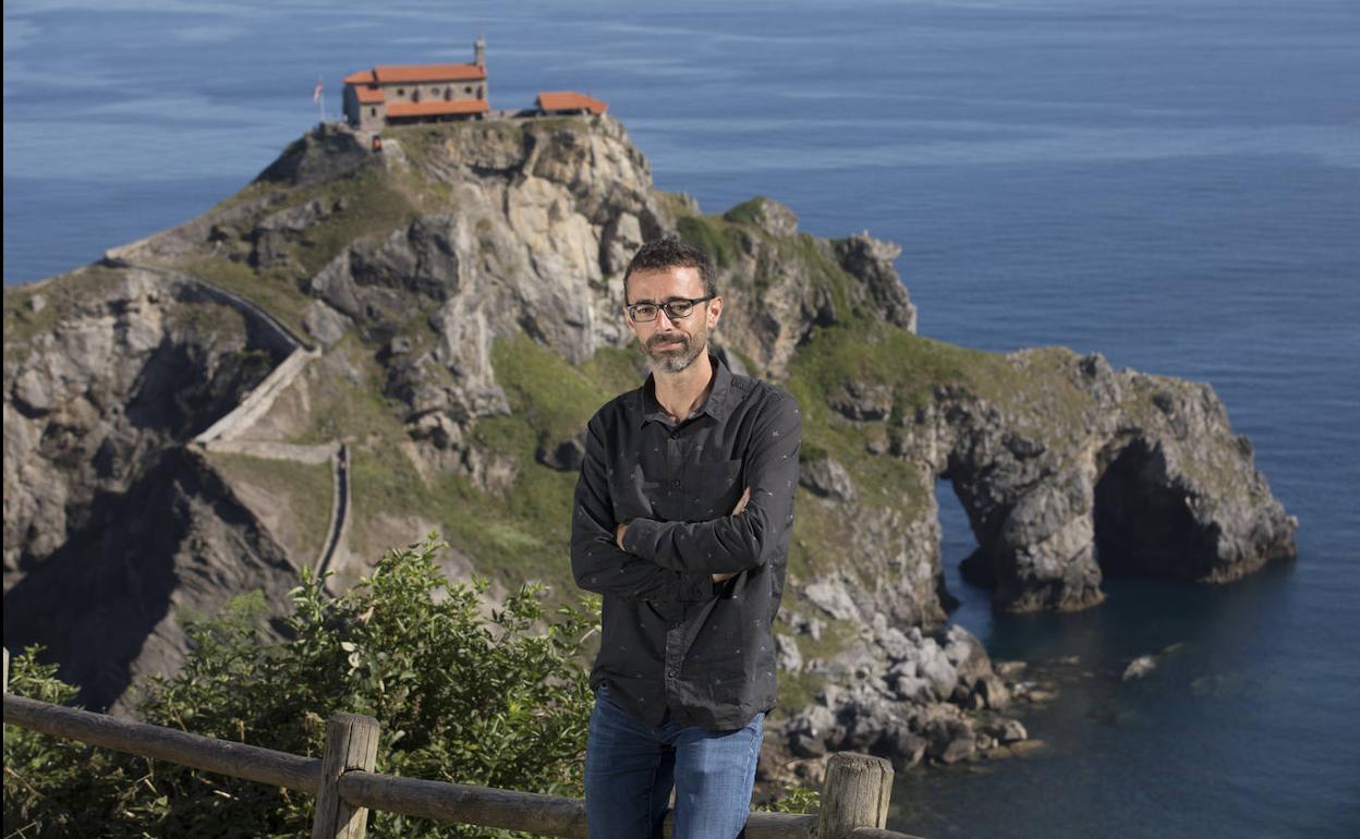 El escritor donostiarra Ibon Martín con la ermita de San Juan de Gaztelugatxe al fondo.