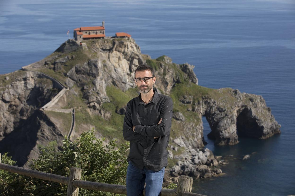 El escritor donostiarra Ibon Martín con la ermita de San Juan de Gaztelugatxe al fondo. :: Asís Ayerbe