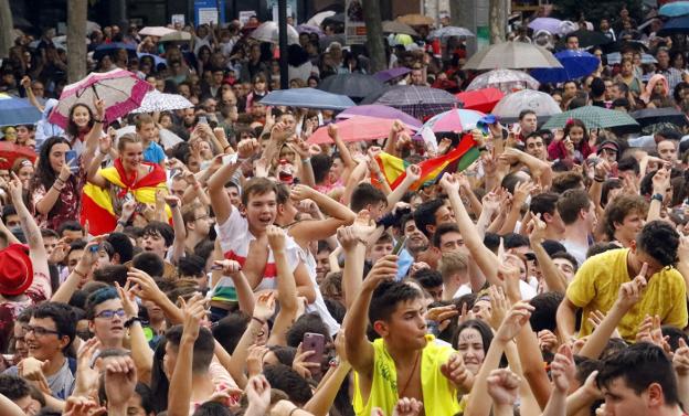 Los más jóvenes celebran el inicio de las fiestas en la plaza del Ayuntamiento, rodeados de algunos paraguas. 