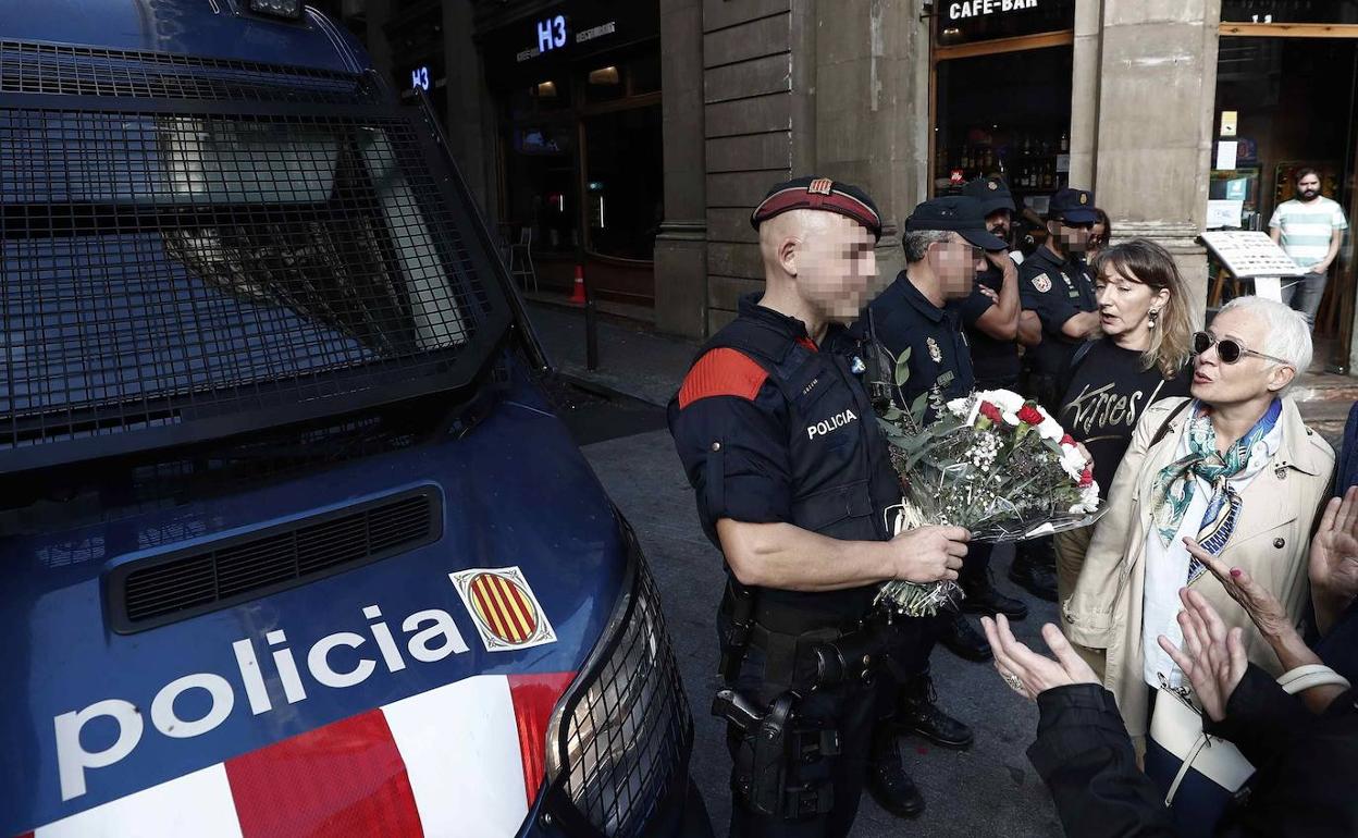 Unas mujeres ofrecen a un mosso un ramo de flores en señal de agradecimiento tras los disturbios de Barcelona.