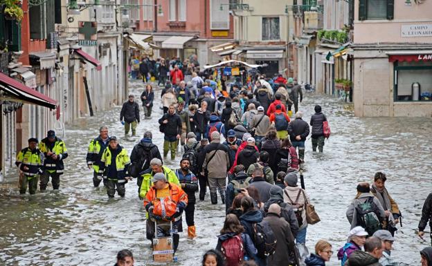 Los turistas y los vecinos caminan por las calles inundadas de Venecia como pueden. 