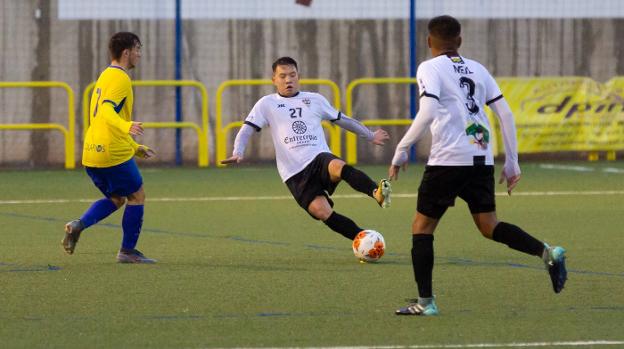 Chen intenta controlar el balón ante la presencia de un rival.