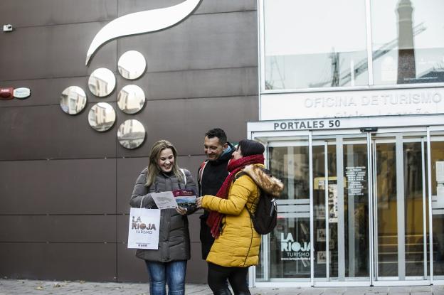 Tres visitantes miran unos folletos tras salir de la Oficina de Turismo en Logroño.