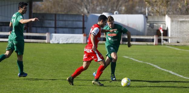 Dani Suárez, el local más vertical, conduce el balón ante la presión de un defensor rival. 