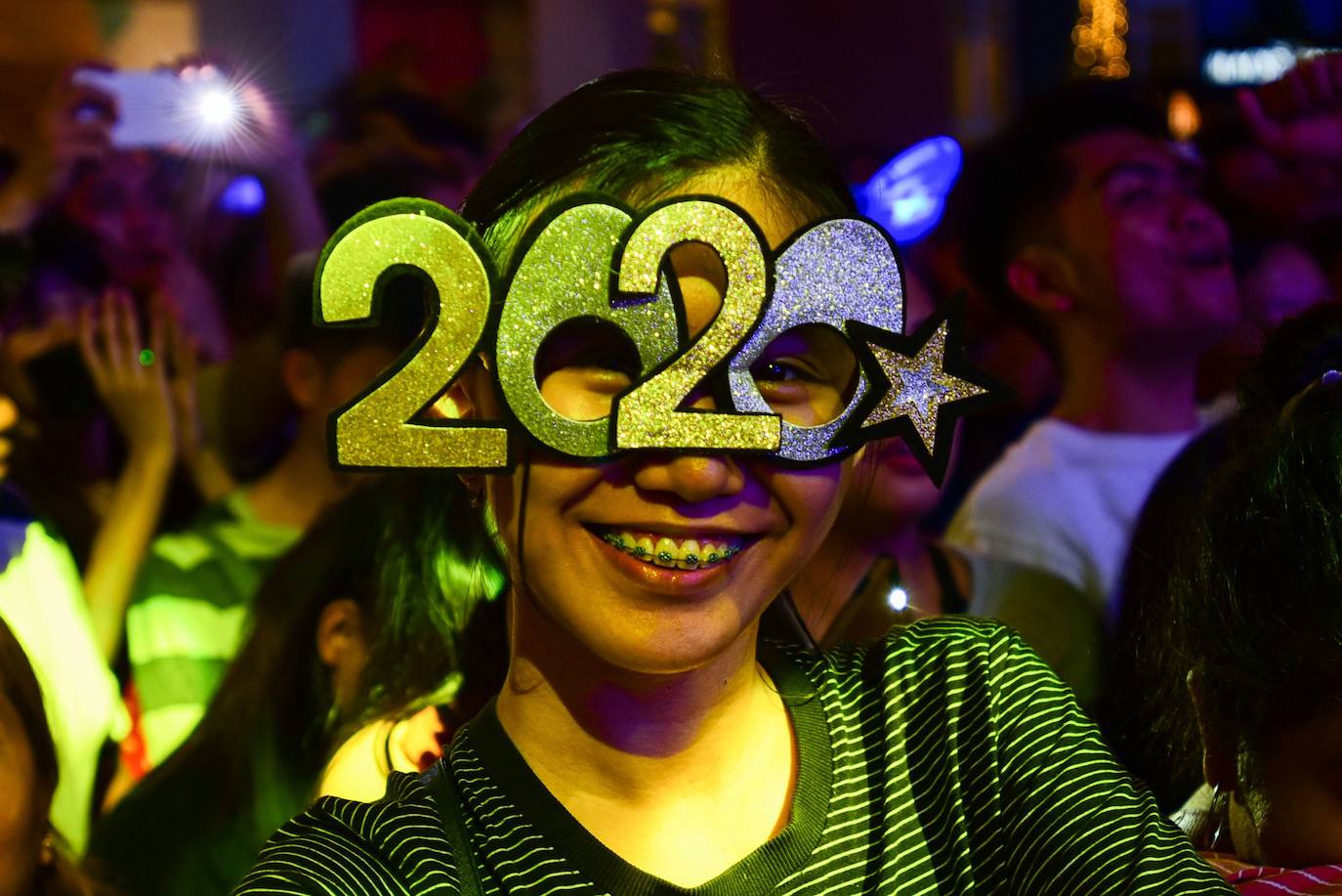 Una joven celebra la llegada del año 2020 en Manila con unas gafas conmemorativas.