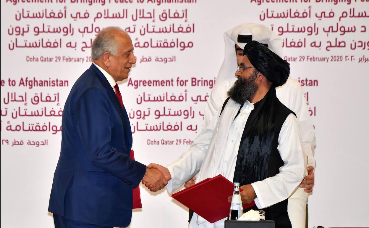 Zalmay Khalilzad y el mulá Abdul Ghani Baradar sellan el acuerdo.