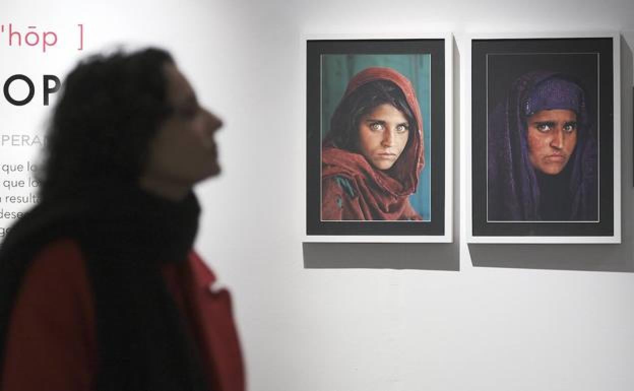 Una mujer de perfil, junto a los dos retratos que Steve McCurry hizo de Sharbat Gula, la niña afgana. 