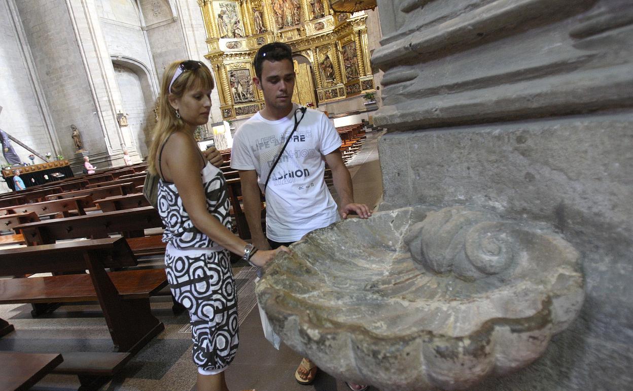 Una pareja contempla la pila del agua bendita, vacía con motivo de la gripe A, en la iglesia parroquial de Santiago el Real, en Logroño, en el 2009. 