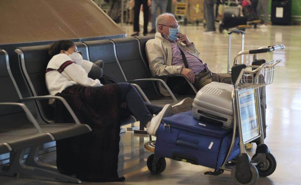 Dos viajeros esperan en el Aeropuerto de Barajas (Madrid).