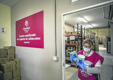 Imagen secundaria 1 - Arriba, María Ángeles Lacarra prepara alimentos mientras una mujer recoge fuera la caja que le han preparado. A la derecha, Pilar, con comida para bebés. A la izquierda, María Ángeles ayuda a Yorleny a empujar el carro. 