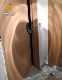 Imagen secundaria 2 - La Guardia Civil, frente a la vivienda. Abajo, detalle de los daños en la puerta.