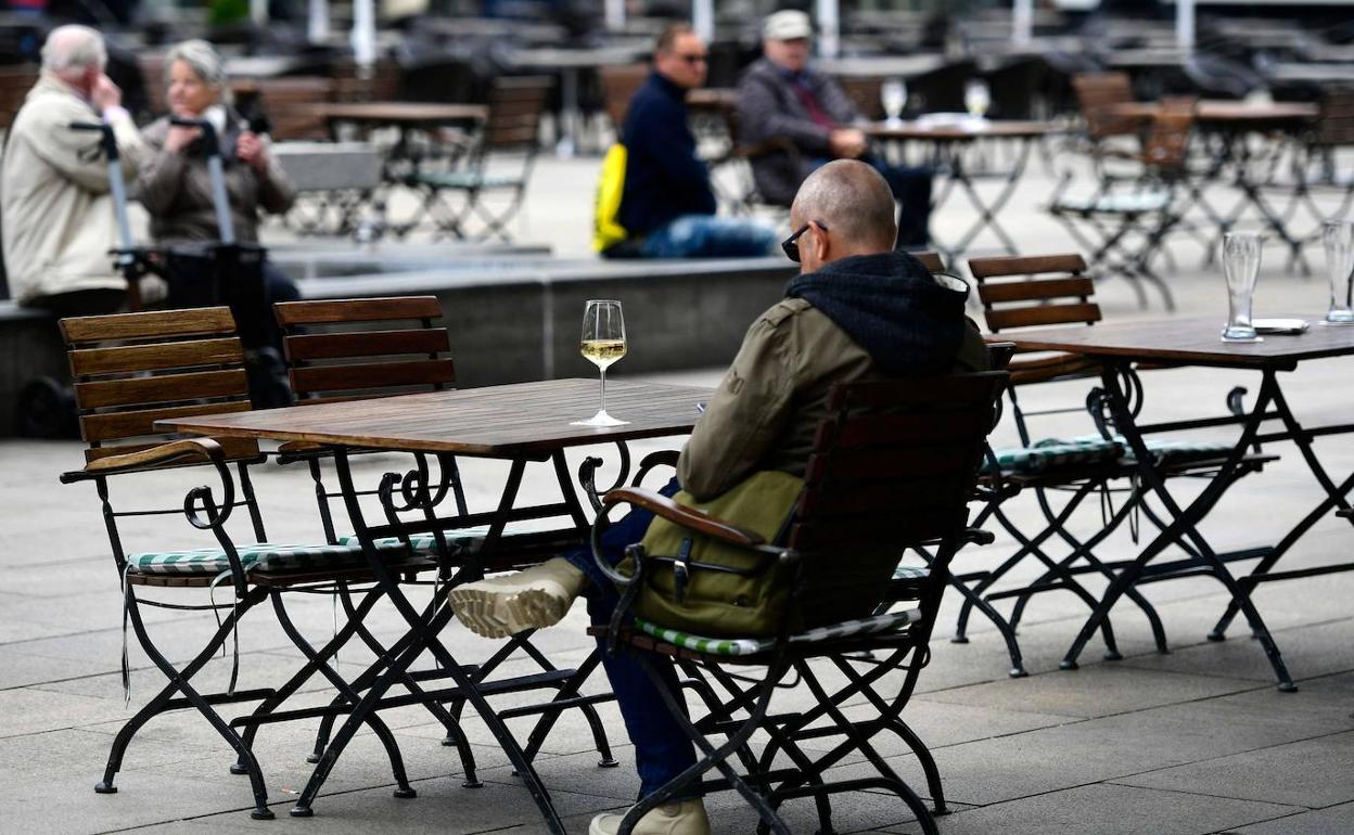 Un hombre toma una copa de vino en una terraza. 