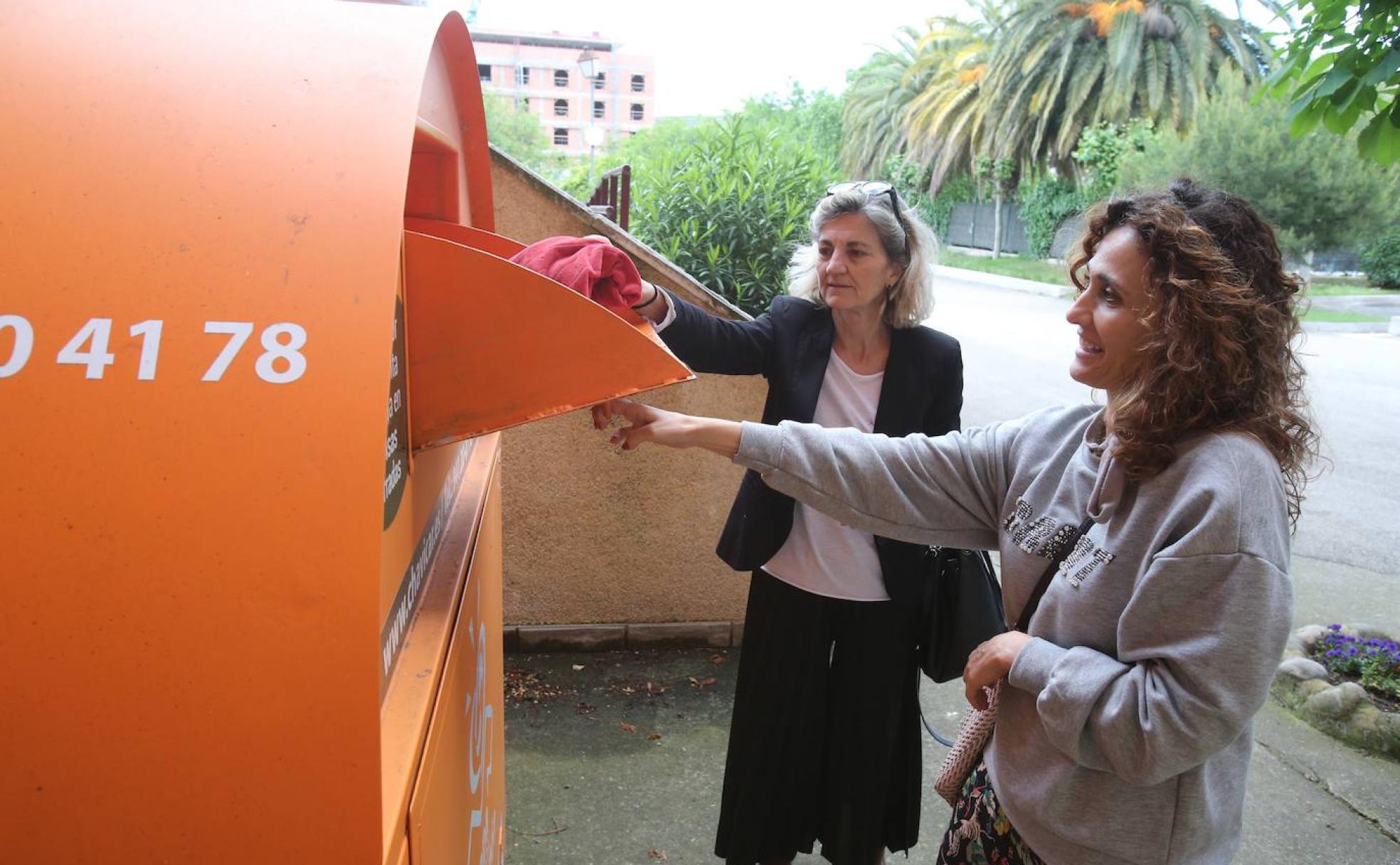 Unas vecinas depositan ropa usada en un contenedor de Chavicar situado en los Salesianos. 