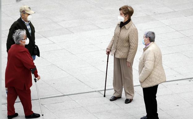 Un grupo de personas mayores hablan con distancia social en la calle. 