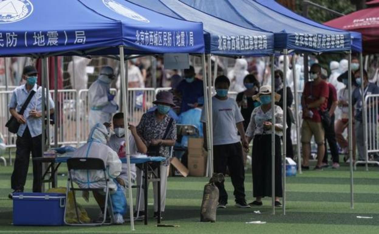 Residentes o gente que visitó el mercado de Xinfadi hacen cola para hacerse el test de coronavirus en el pabellón deportivo de Guang'an, en Pekín. 