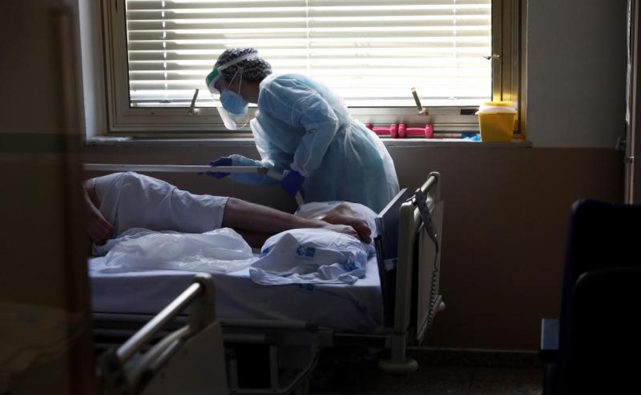 Una sanitaria asiste a una persona en una de las tres unidades de hospitalización con pacientes con Covid aún operativas en el área de medicina interna del Hospital Gregorio Marañón de Madrid. 