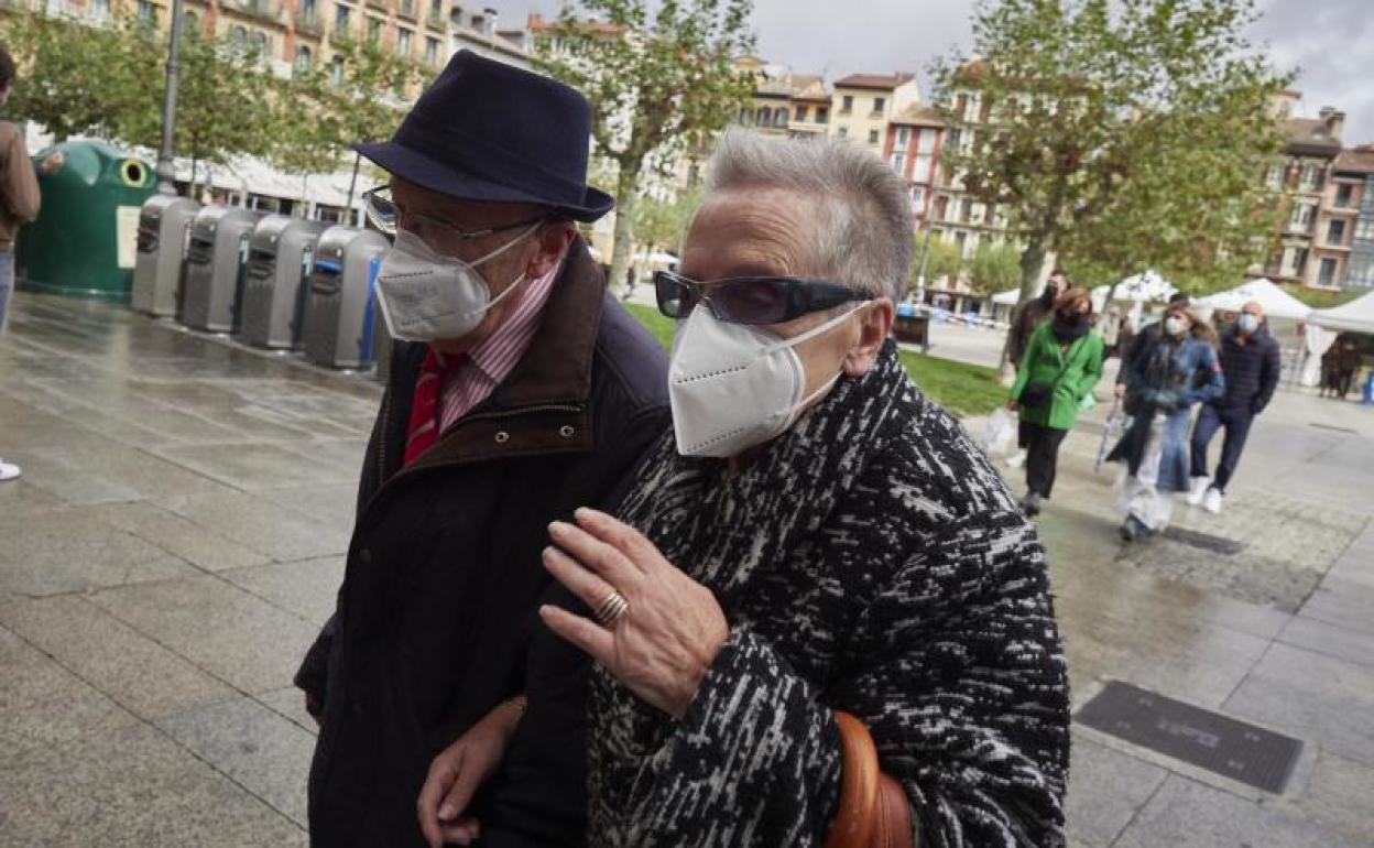 Transeúntes pasean por una calle de Pamplona protegidos con mascarilla.