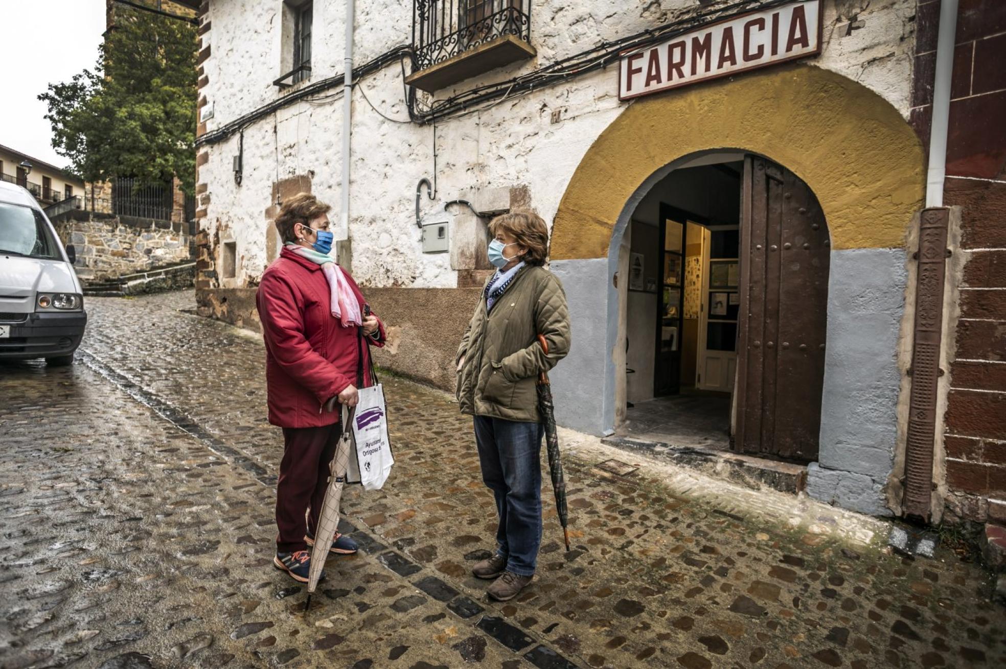 Ángeles Sánchez y Paloma Martínez se saludan a la entrada de la farmacia de Ortigosa. 