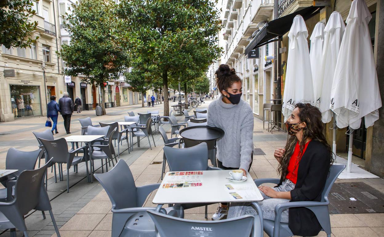 Una camarera atiende una terraza de un bar de Vitoria.