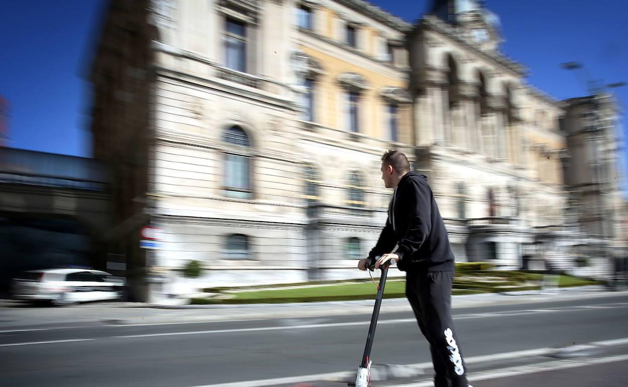 Un joven en patinete eléctrico circula por el carril bici.