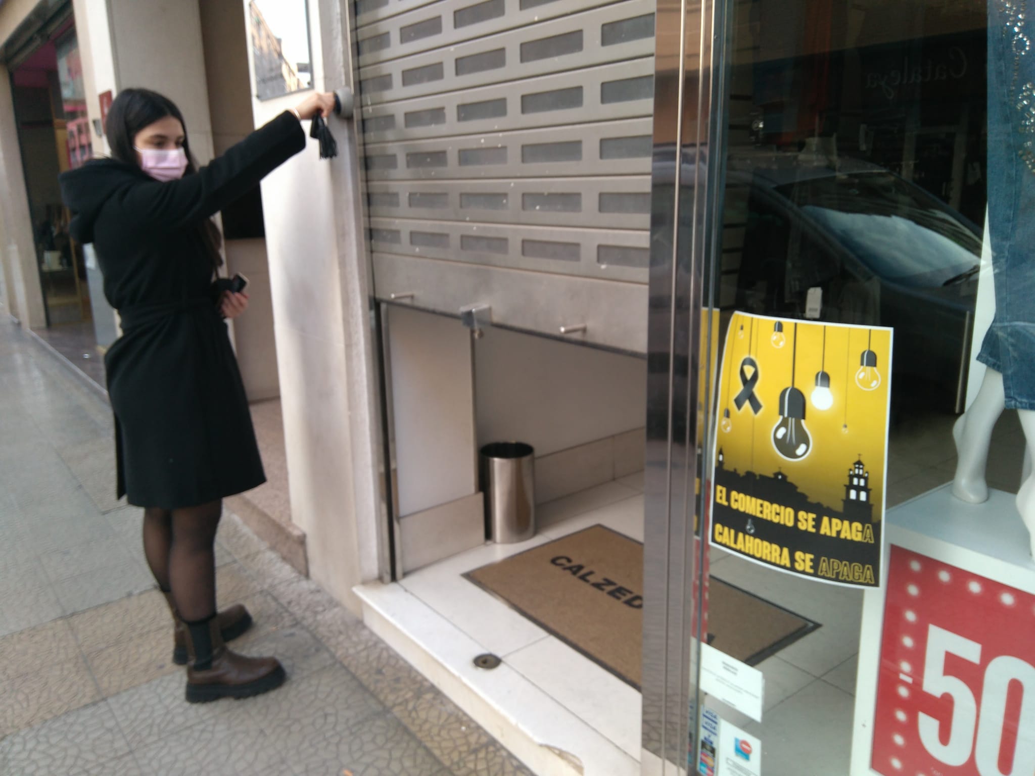 Una trabajadora baja la verja de una tienda de Calahorra.