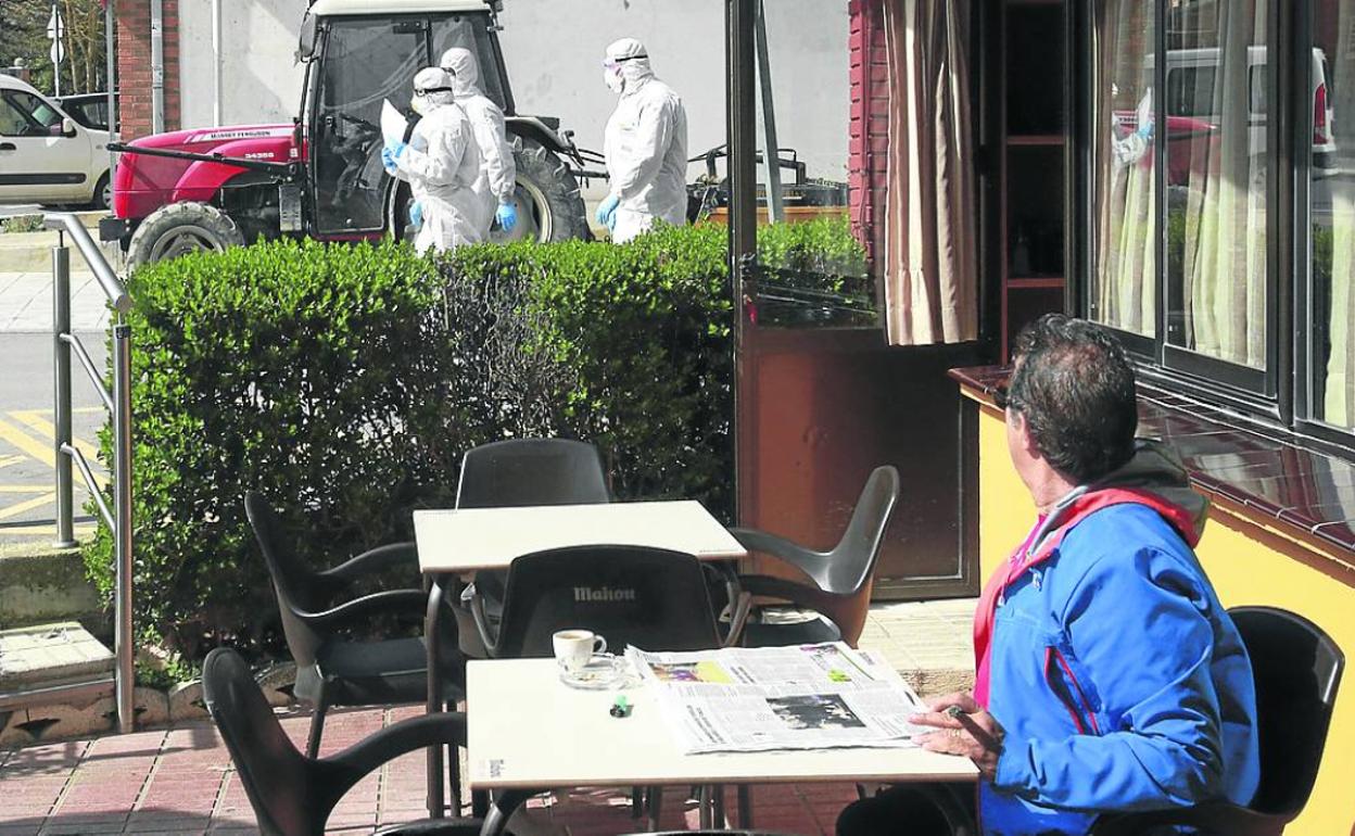 Un vecino se toma un café, antes del cierre de la hostelería, mientras observa a los sanitarios. 