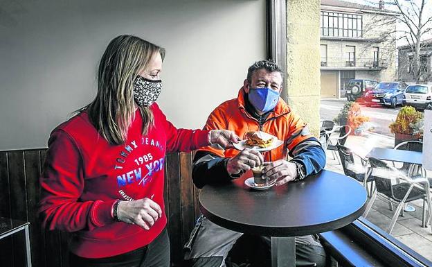 Imagen principal - La camarera del Bar Chakal sirve un bocadillo a un cliente, Sheila Ansan, a las puertas de su taberna, el día antes de su apertura y Juan Rodríguez, dueño del Batzoki, con la prensa en la mano.