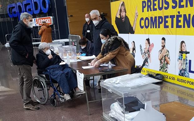 Cristina, de 89 años, en silla de ruedas y con su mantita abrigándole las piernas, ha acudido a votar junto a su hijo, Jordi, de 65.