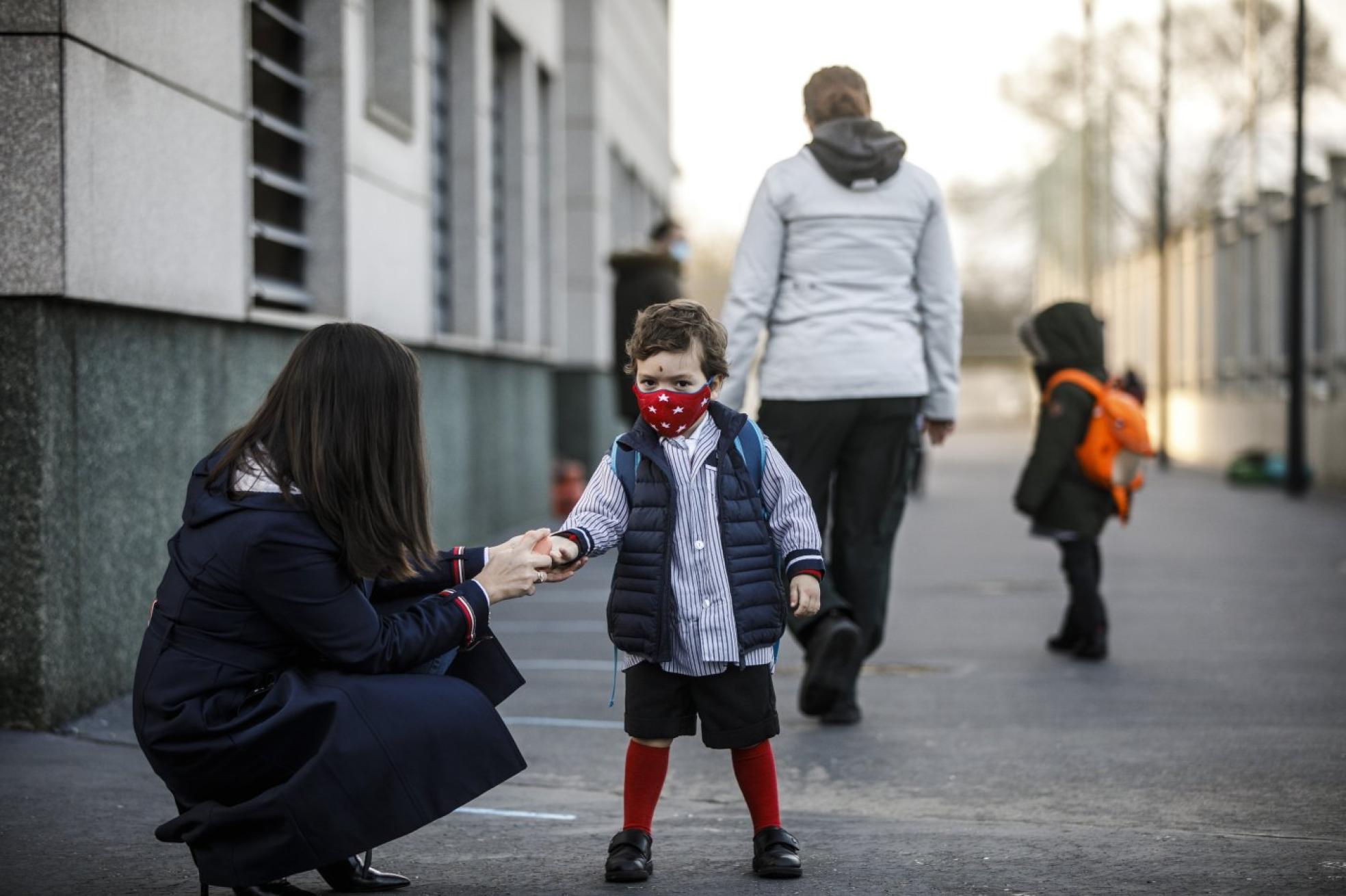 Una madre pone la mascarilla y gel hidroalcohólico en las manos de su hijo antes de entrar al colegio. 