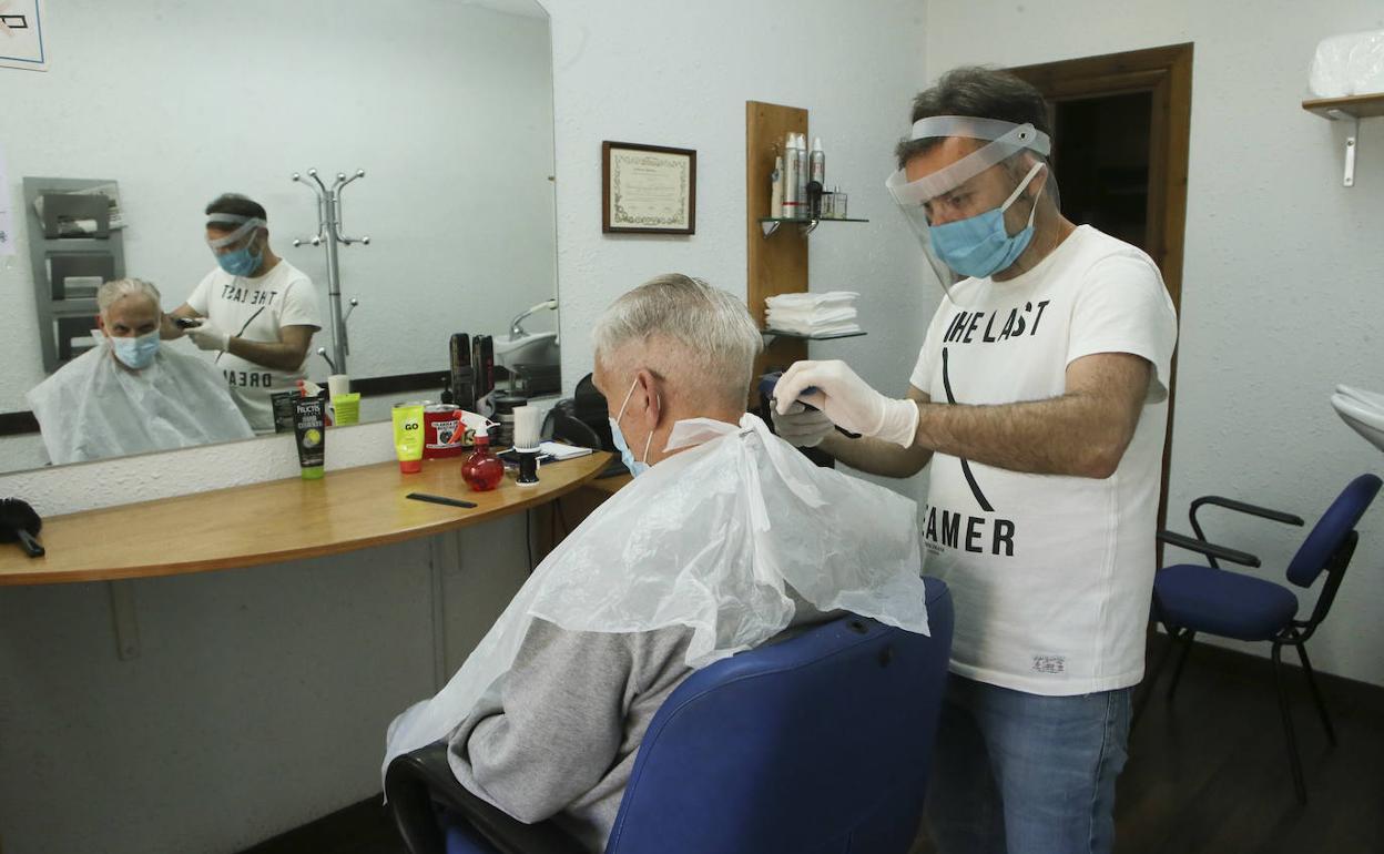 Un peluquero y su cliente en su peluquería durante la pandemia.