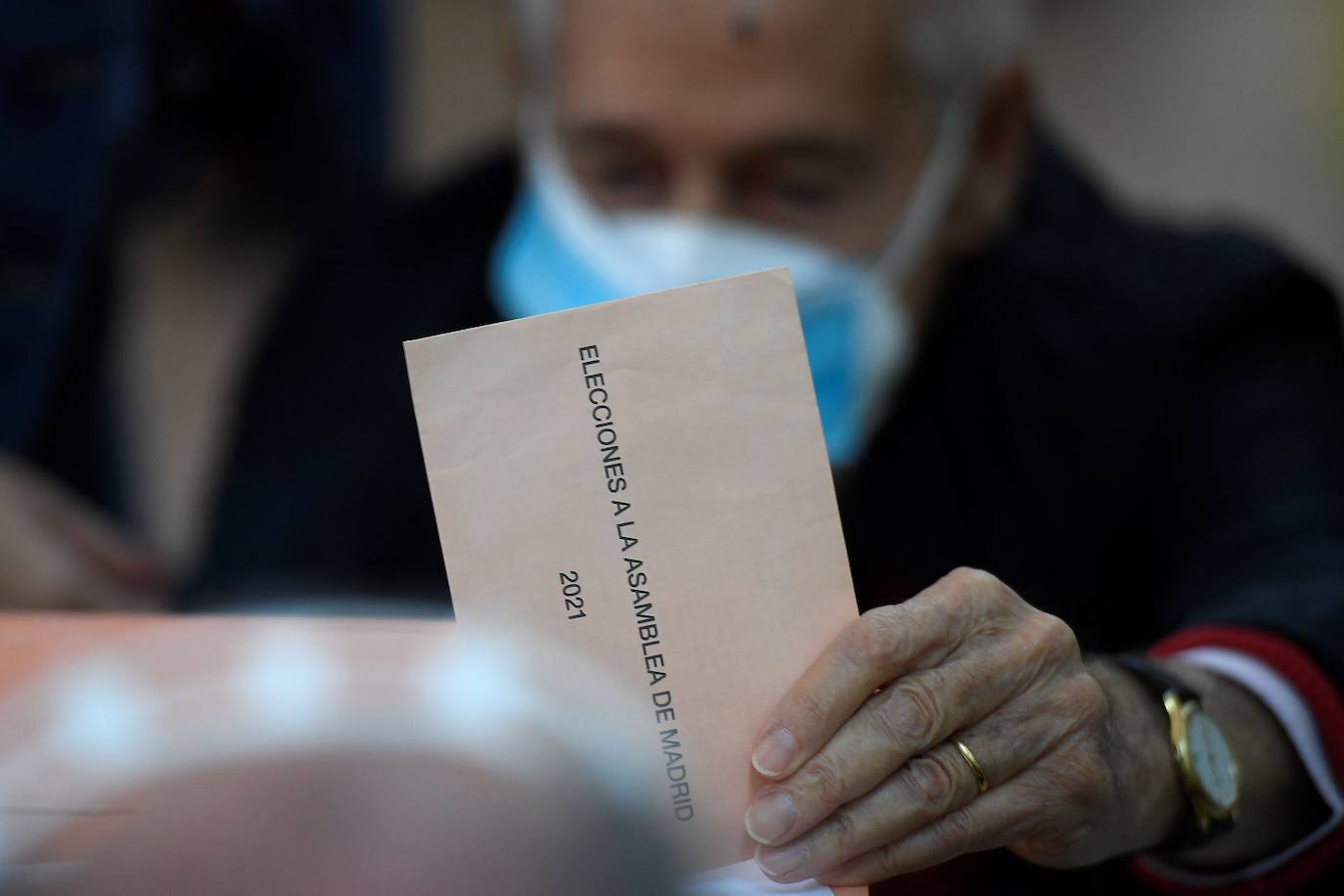 Un hombre deposita su voto en un colegio electoral en Madrid, para unas elecciones en los que están convocados 5.112.658 electores.