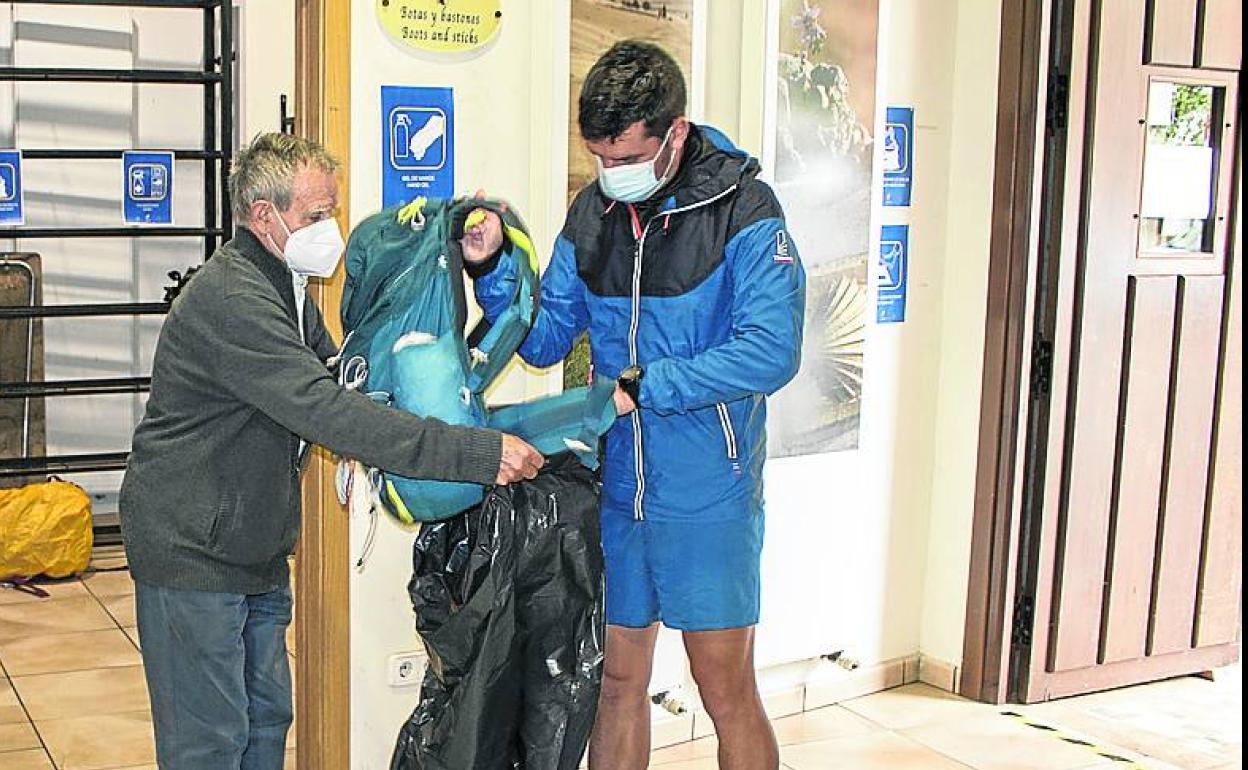 José María Rodrigo ayuda a un peregrino con su bolsa. 