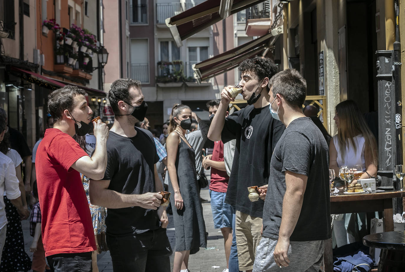 Un grupo de amigos toma vino en el típico jarrito de San Bernabé, en la calle Laurel. 
