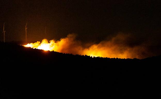 Imagen principal - El fuego de madrugada, Dos vecinso de Villarroya mirando el monte esta mañana, y unaimagen de los trabajos nocturnos