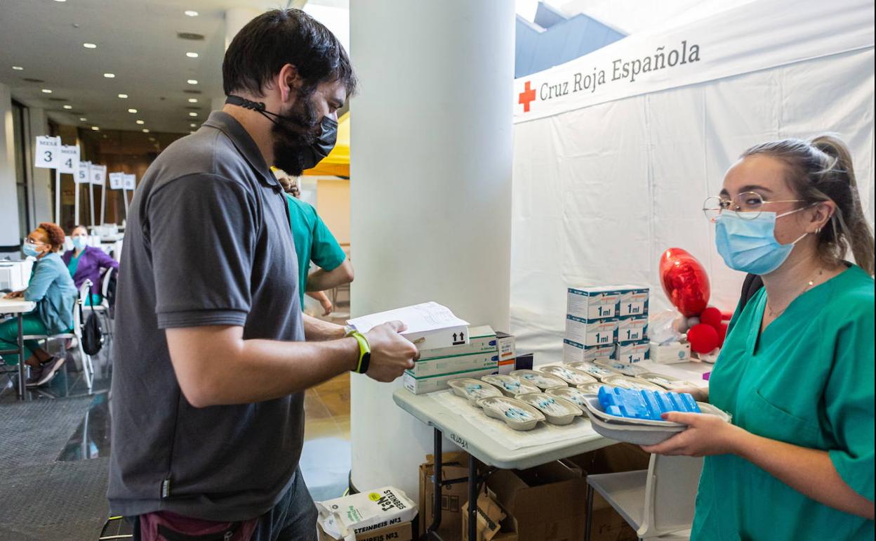 Un trabajador de Riofarco entrega a una sanitaria viales de vacunas para su administración en el Riojafórum. 