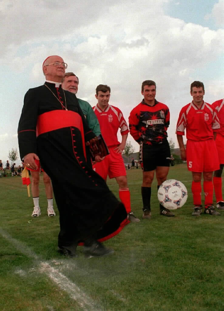 El cardenal realiza el saque de honor en el partido que sirvió para inaugurar el campo de fútbol de Baños y en el que se enfrentaron el Bañuelos y el Logroñés B.