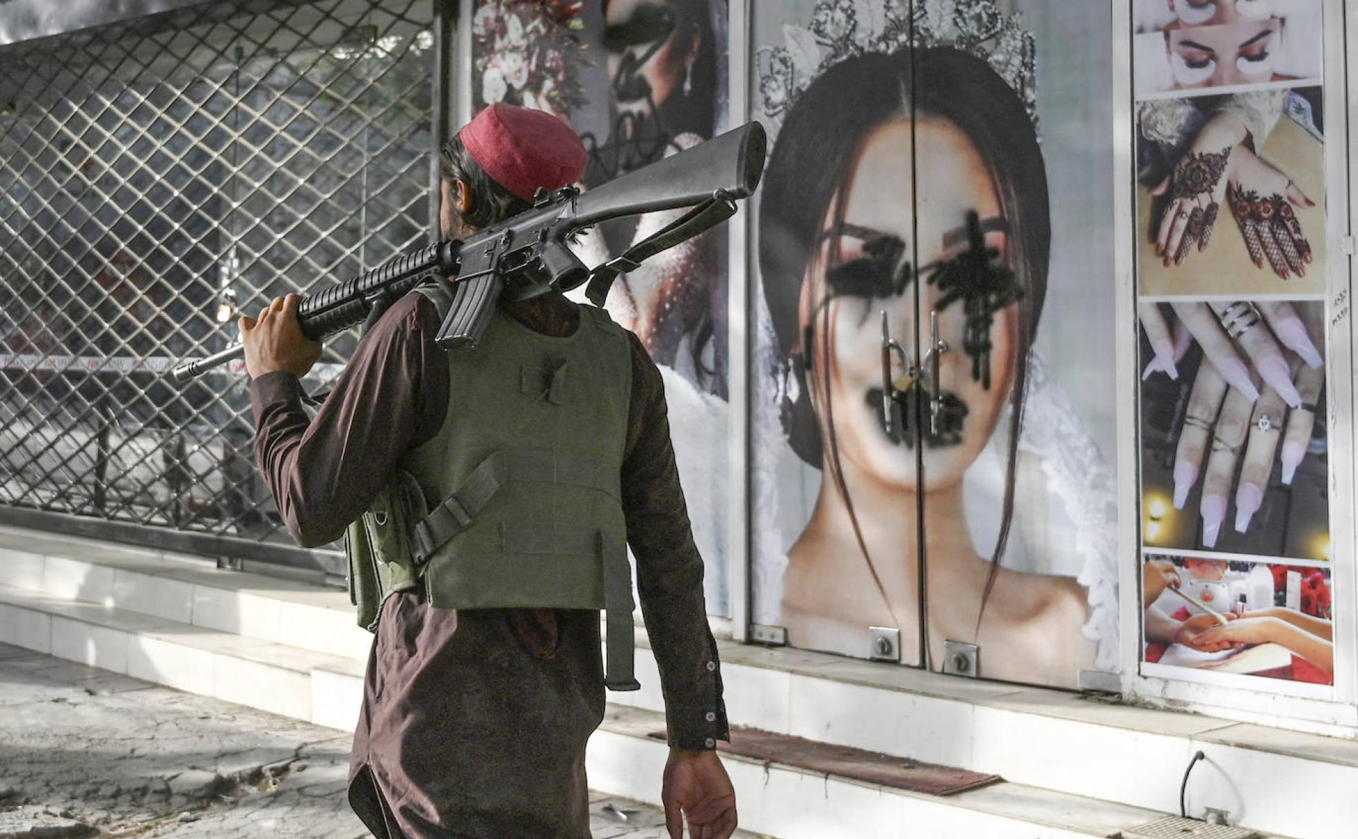 n talibán pasa frente a un salón de belleza en Kabul en el que han sufrido pintadas las fotos de mujeres.