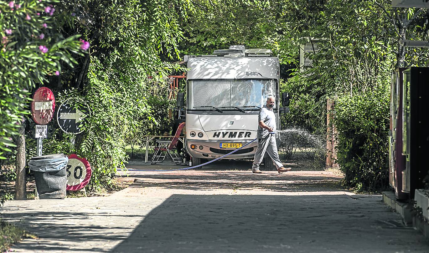 Autocaravana calzada y gente sentada fuera, una práctica no permitida.