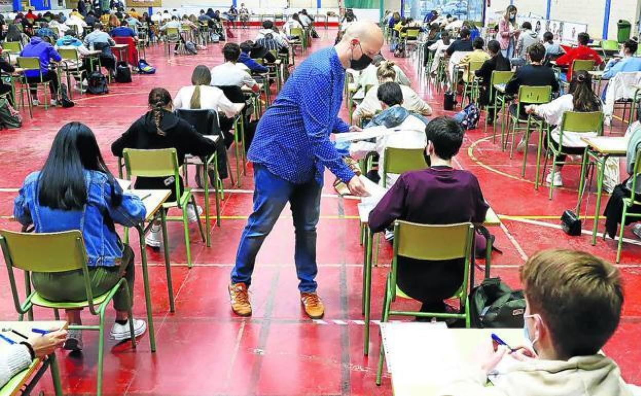 Un profesor reparte exámenes en un aula. 