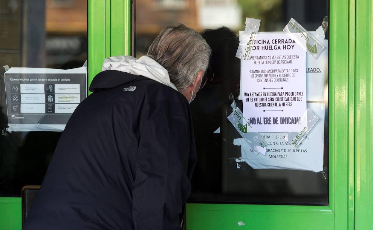 Un cliente observa el interior de una oficina bancaria cerrada por la huelga en Unicaja por el ERE.